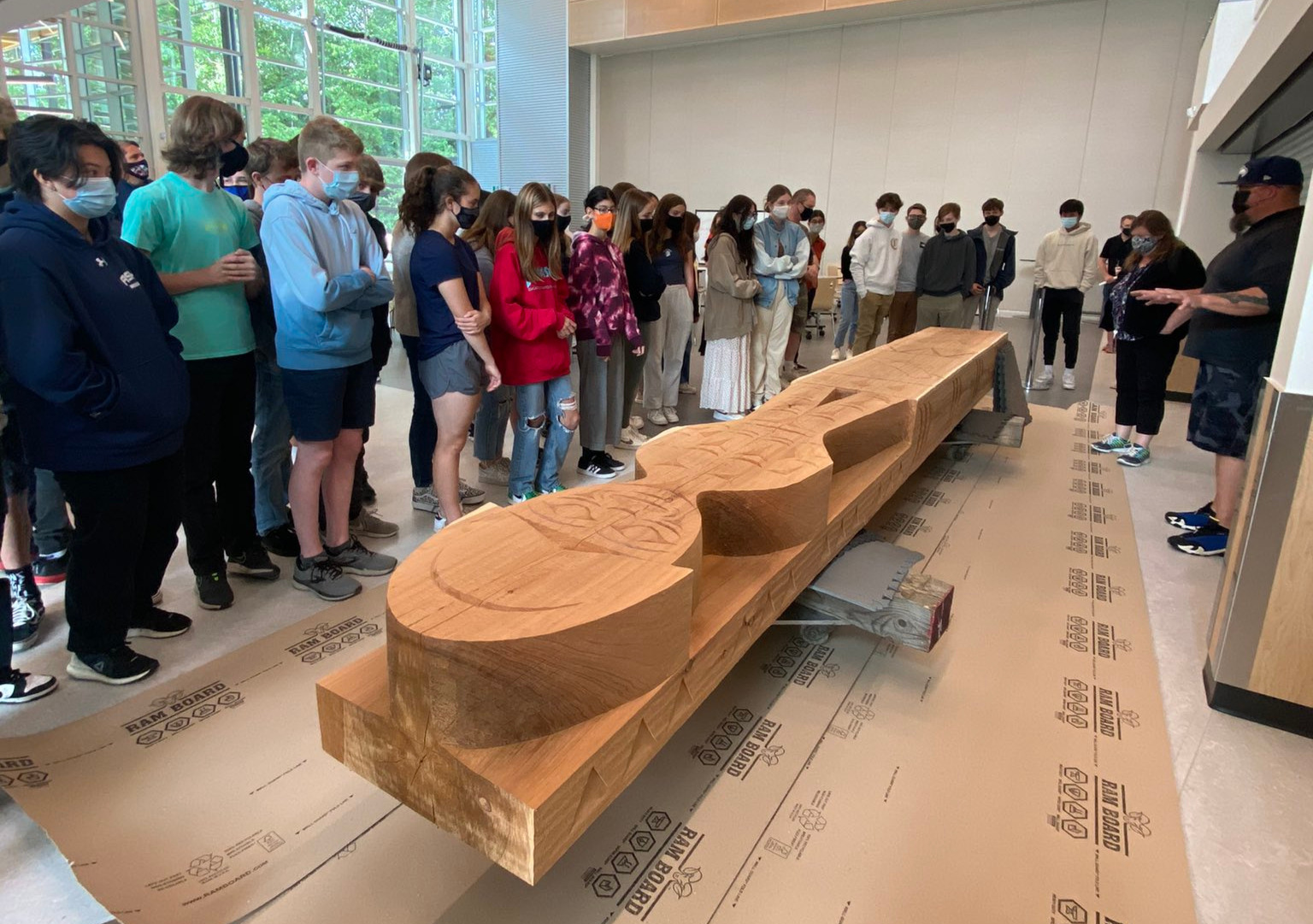 a group of students gathered around and learning about the Welcome Figure's history and significance